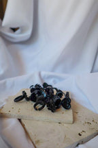 Black heart shaped glue rings on a wooden block with a white cloth background