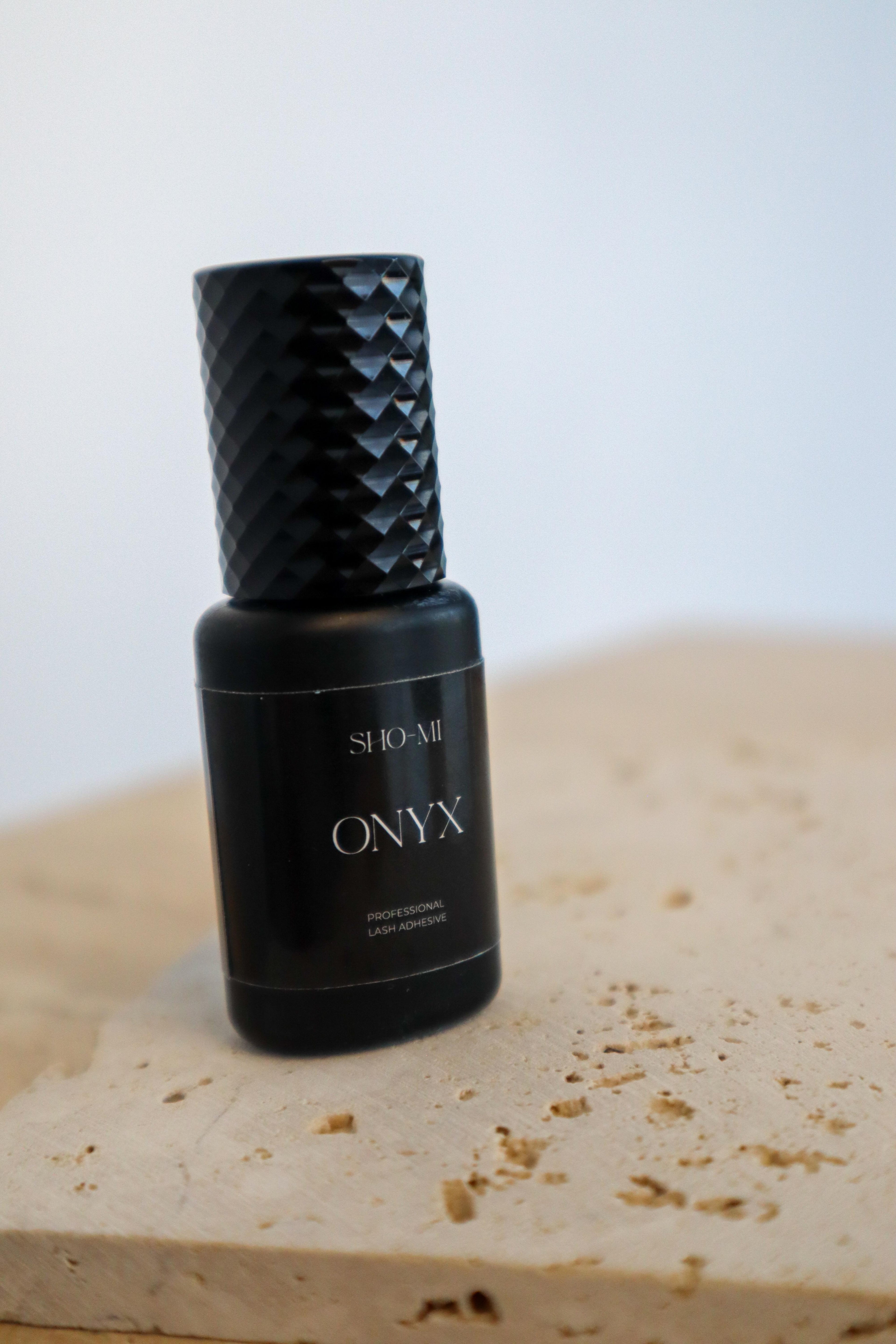 Black bottle labeled 'Onyx' by SHO-MI on a light surface with a white background