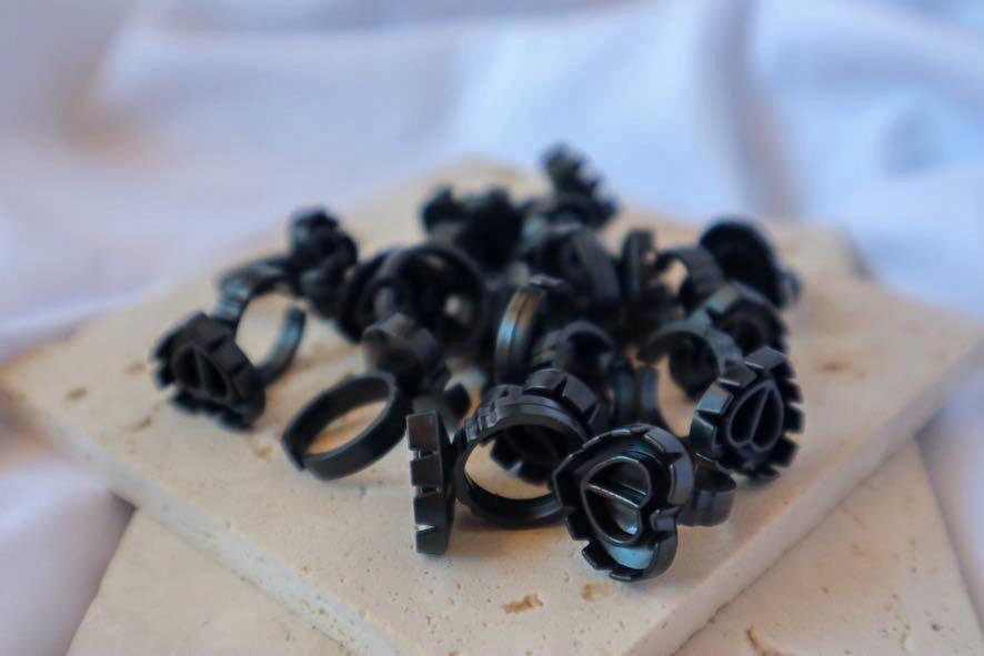 Black glue holder rings on a beige surface with a blurred white background