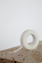 Roll of clear micropore tape on a textured surface with a white background