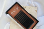 Eyelash extension kit with 'SHO-MI' branding on a light fabric background