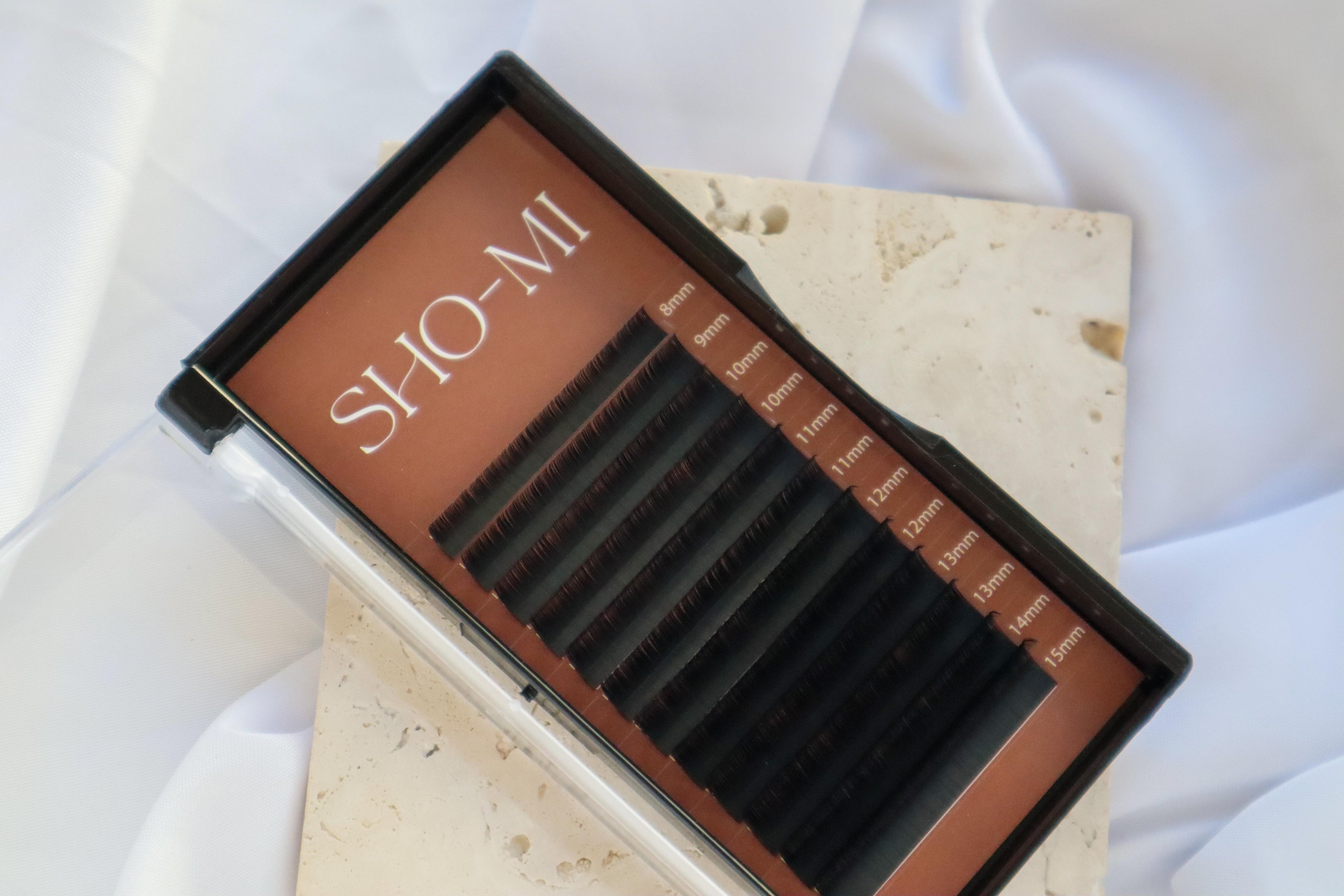 Eyelash extension kit with 'SHO-MI' branding on a light fabric background