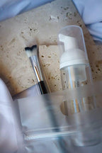 Cosmetic bottle, brush, and sponge on a textured surface