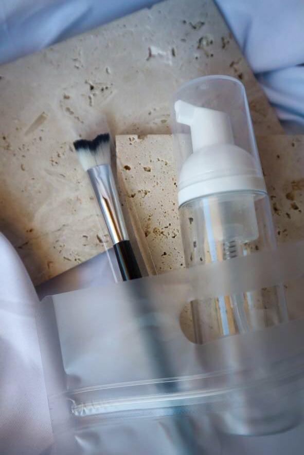 Cosmetic bottle, brush, and sponge on a textured surface