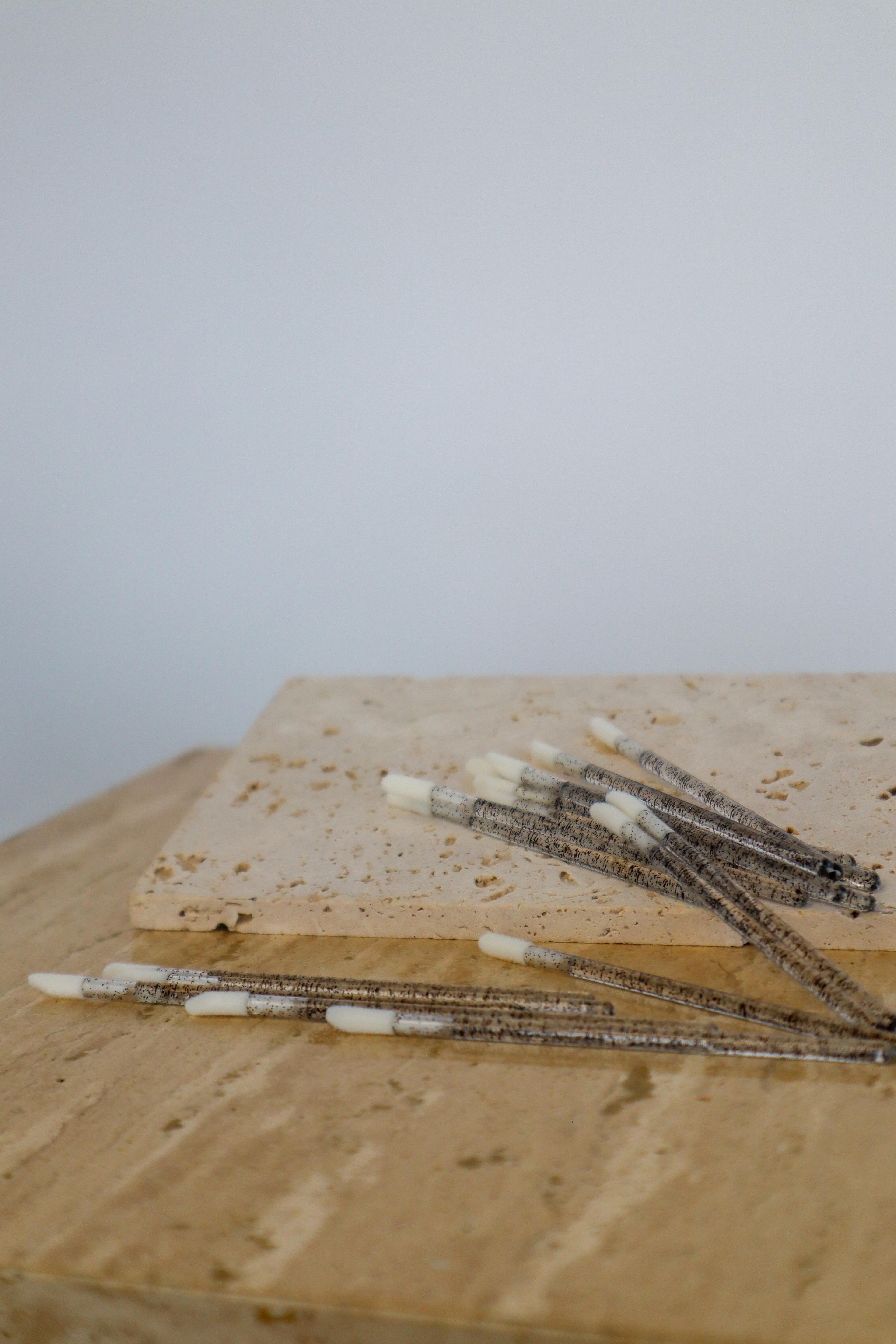 Wooden surface with multiple disposable lip wands on a plain background