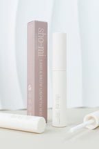 A bottle of Lash & Brow Growth Serum with its packaging box, both featuring a minimalist white and pink design.