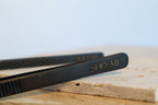 Black SHO-MI branded tweezers on a light surface with a blurred background