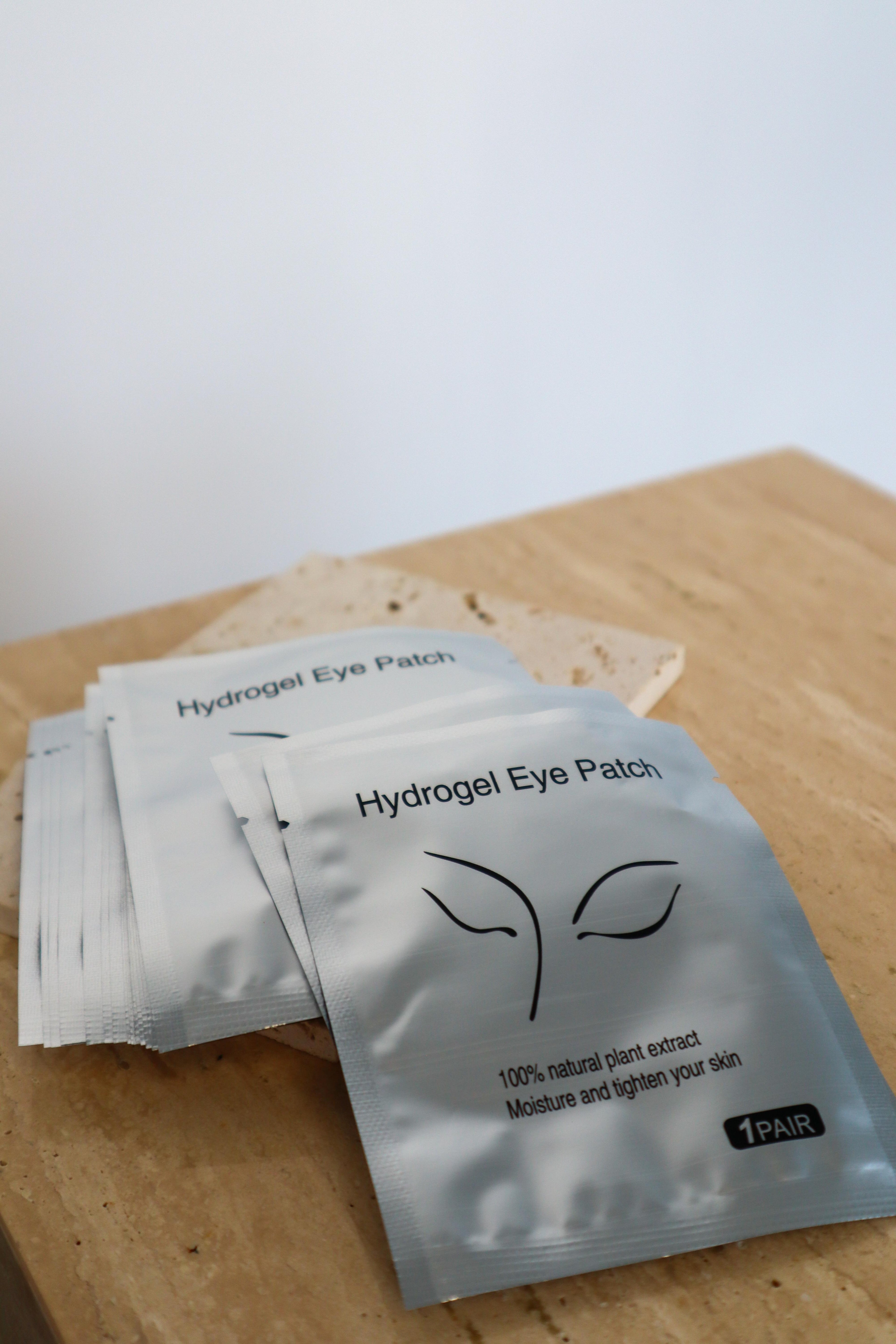 Hydrogel eye patch packets on a wooden surface with a white background