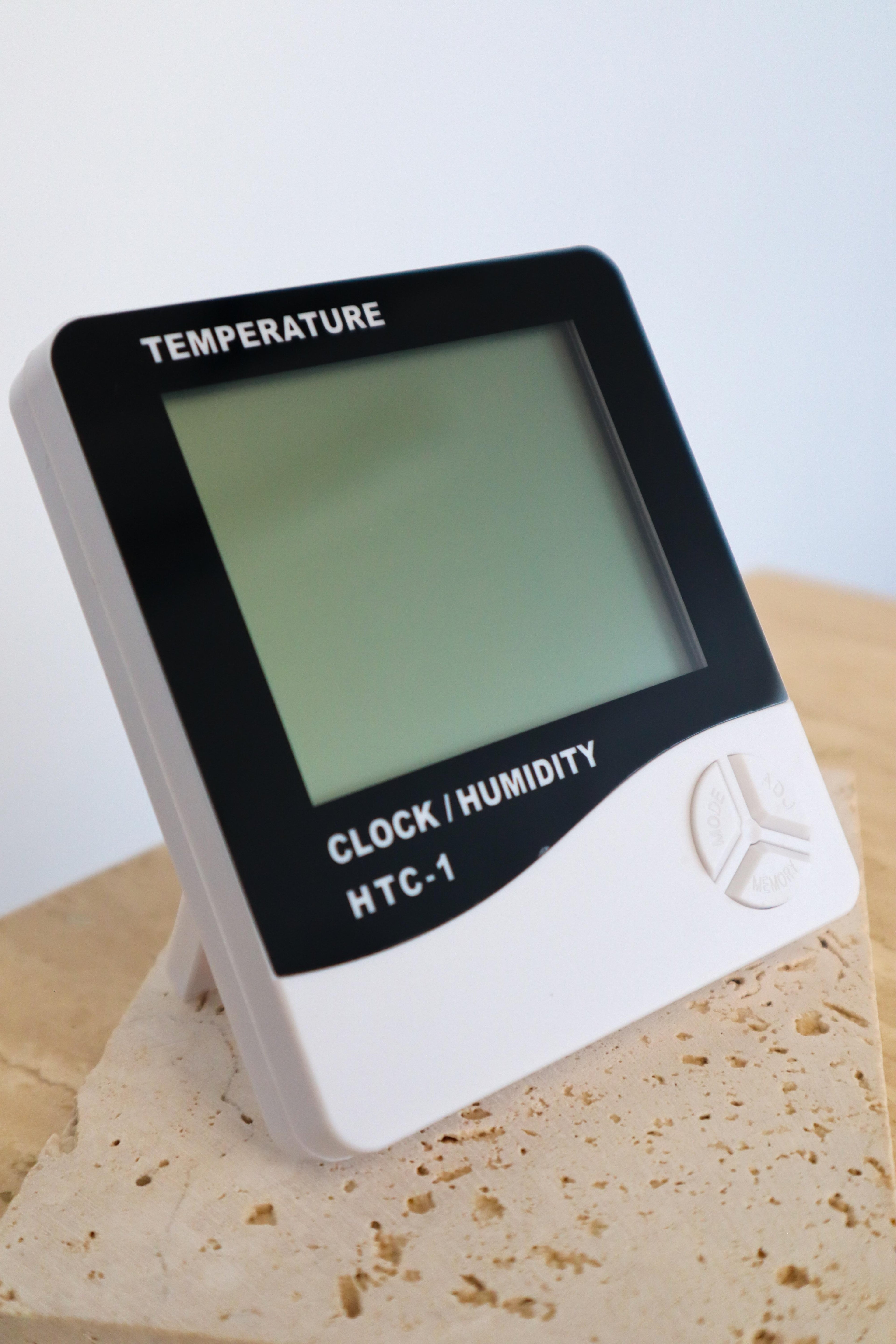 Digital thermometer with temperature, clock, and humidity functions on a wooden surface.