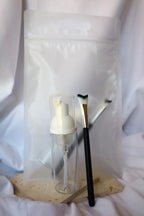 Cosmetic brush and bottle on a wooden block with white background