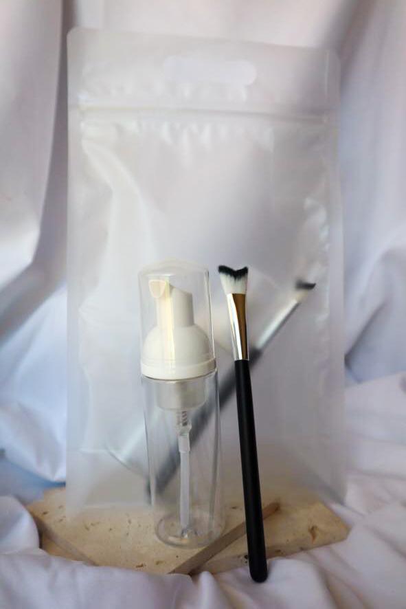 Cosmetic brush and bottle on a wooden block with white background