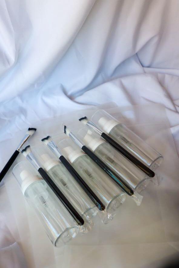 Set of clear plastic bottles with black caps on a white fabric background