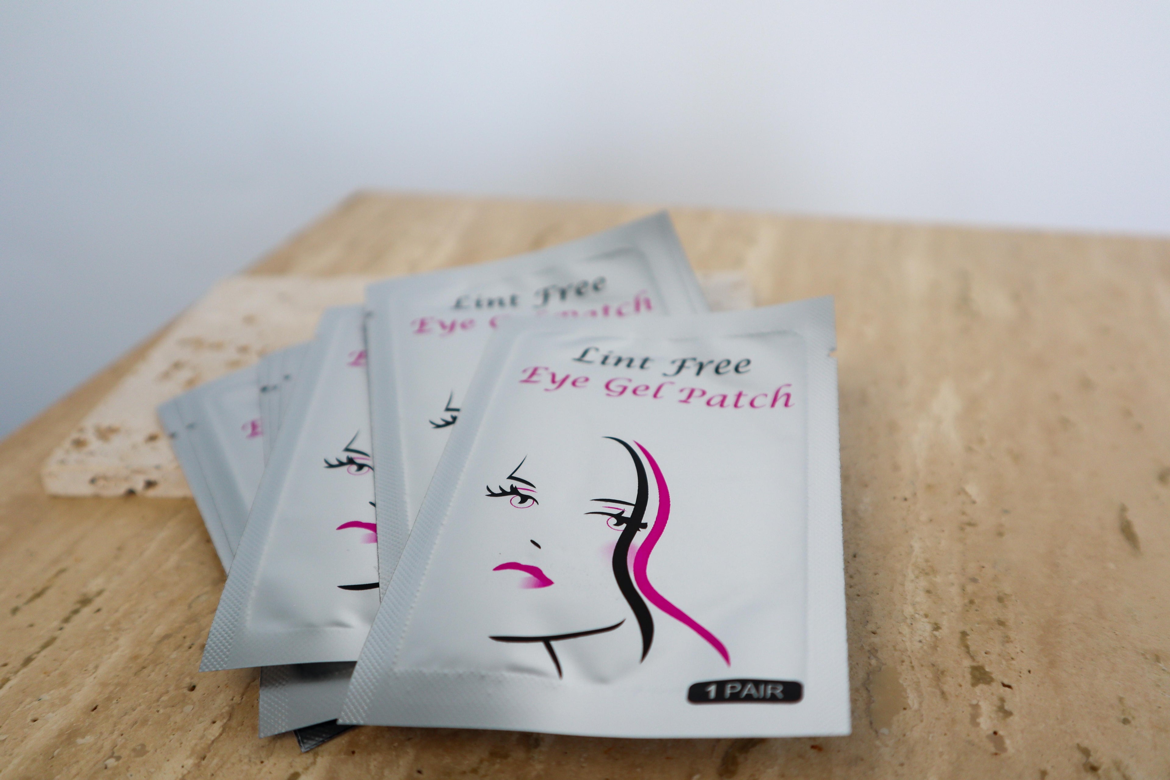 Collection of lint free eye gel patch packets on neutral background