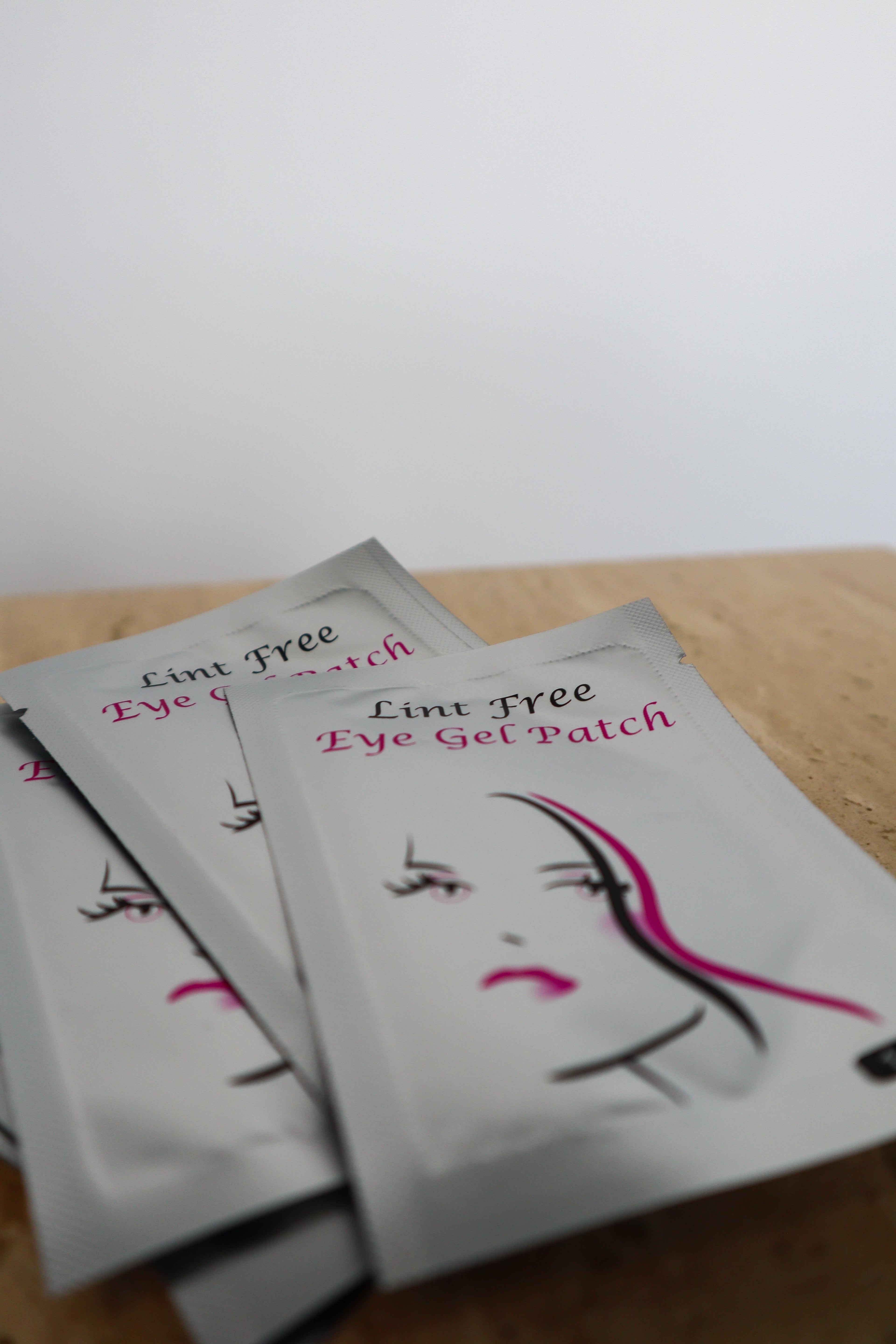 Lint Free Eye Gel Patches on a wooden surface with white background