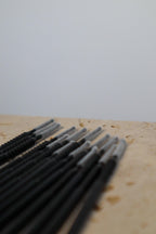 Set of black long tip micro brushes on a wooden surface with a blurred background