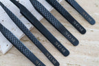 Set of black tweezers with textured handles and 'SHO-MI' branding on a light surface.