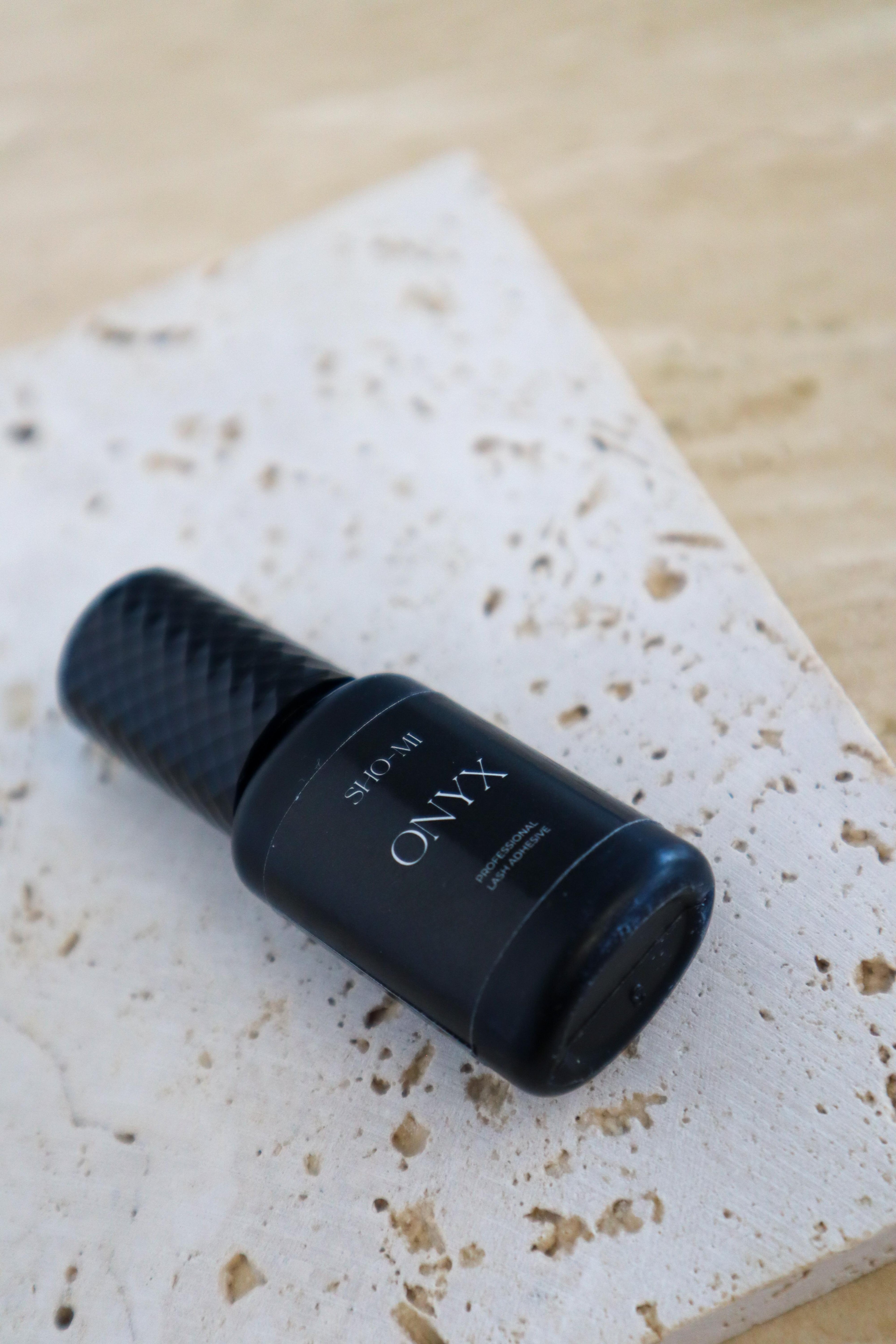 Black bottle labeled 'ONYX' on a textured white surface