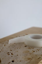 Close-up of a wooden surface with a roll of white micropore lash tape on a light background