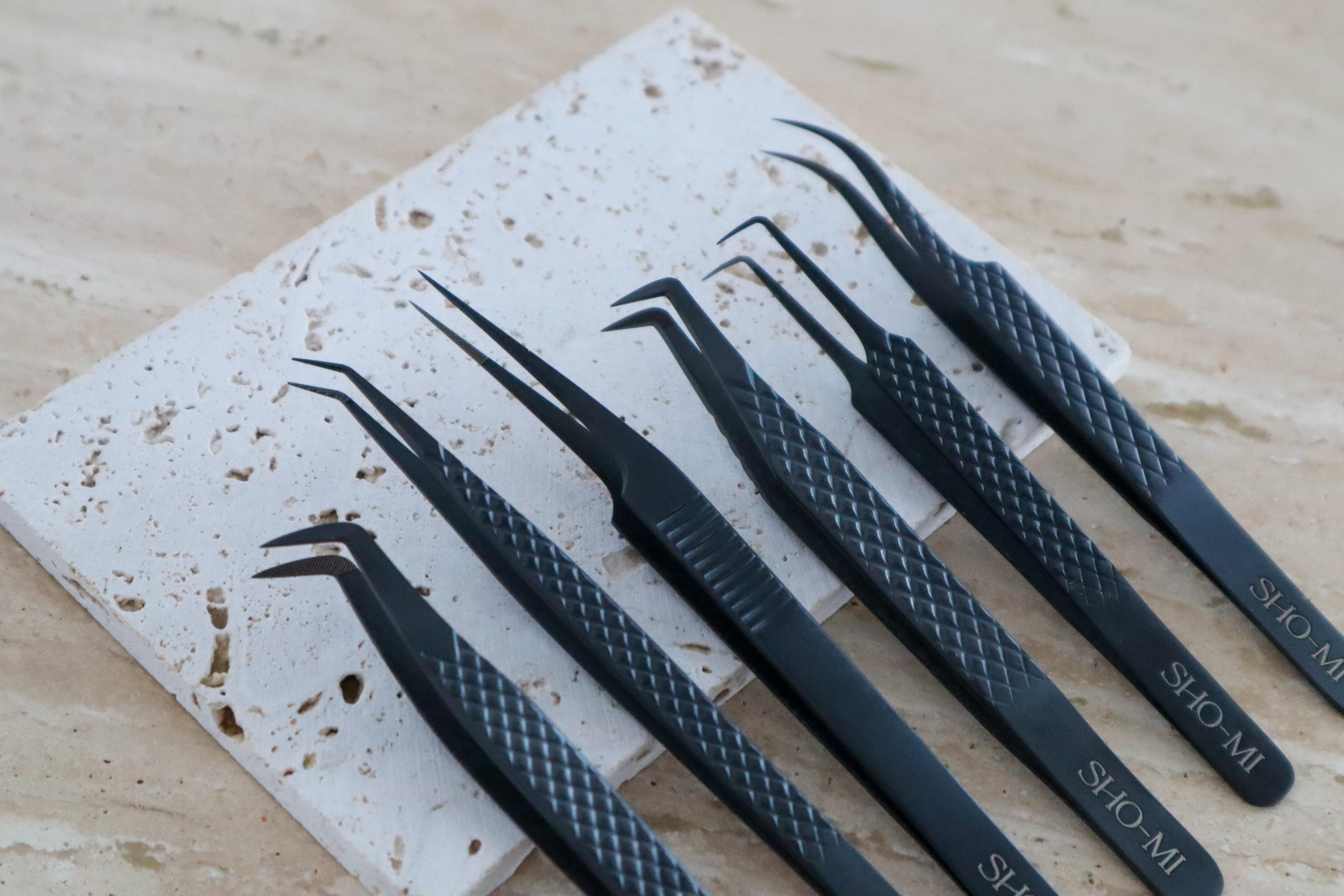 Set of black tweezers on a textured stone surface