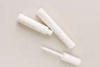 Neutral lash and brow growth serum tubes on neutral background