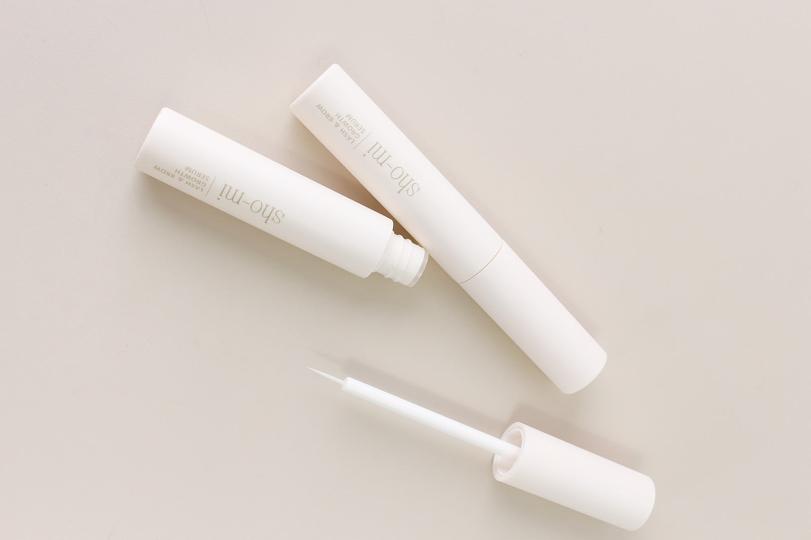Neutral lash and brow growth serum tubes on neutral background