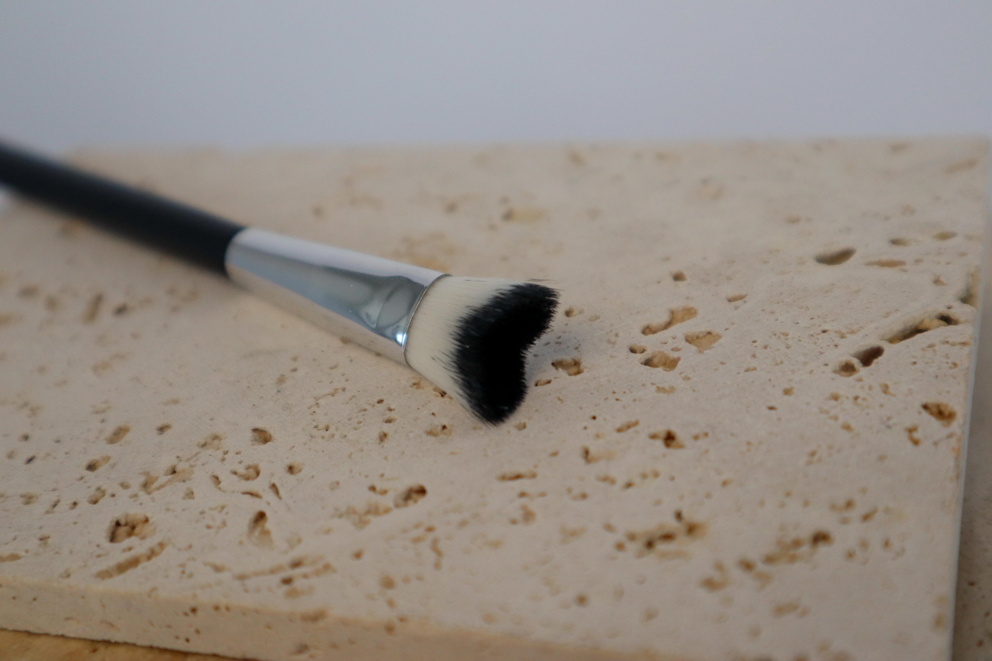 SHO-MI lash cleansing brush on a textured beige surface