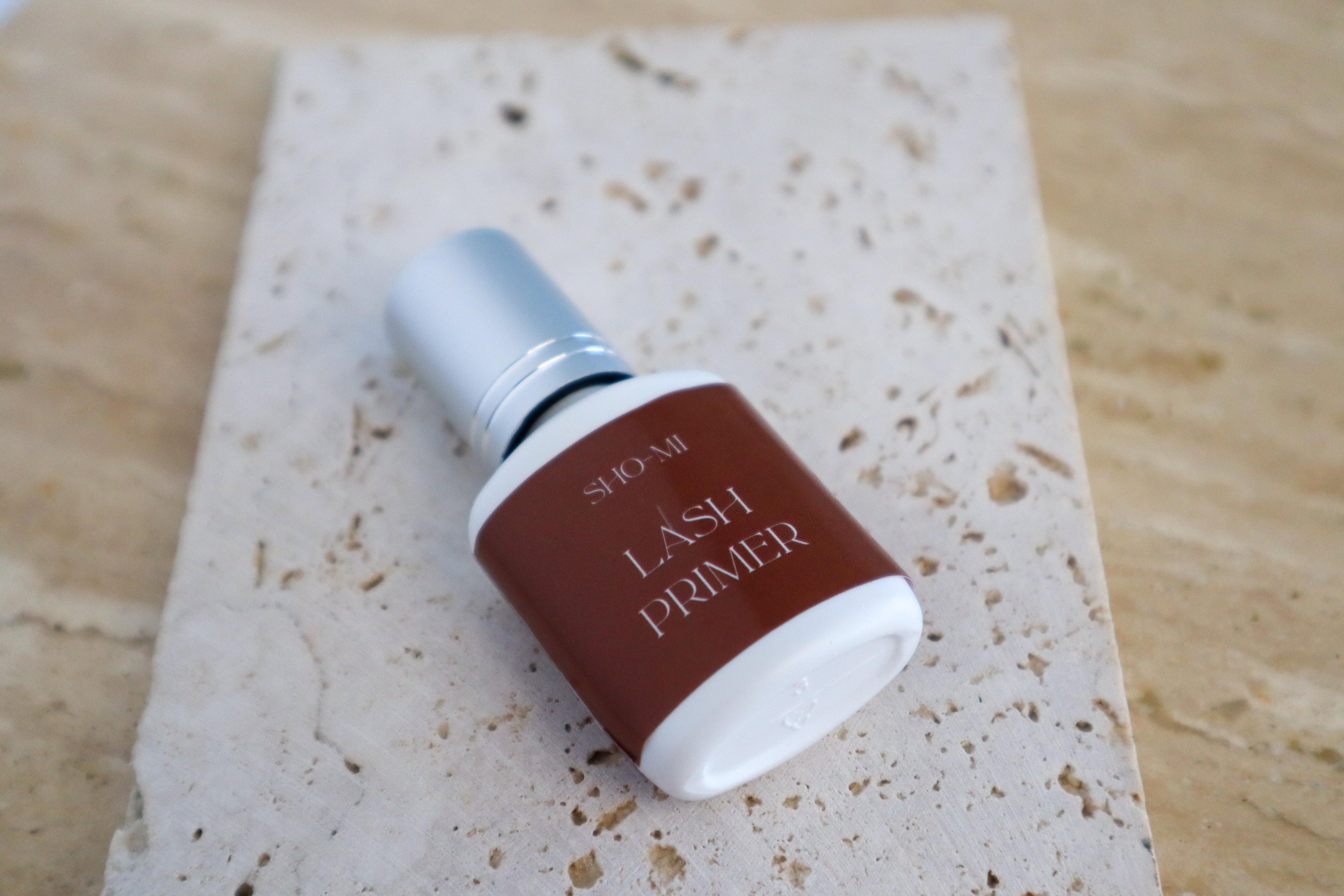 Lash primer bottle on a textured stone surface