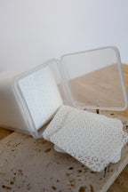 Square container with white lint free wipes on a textured surface