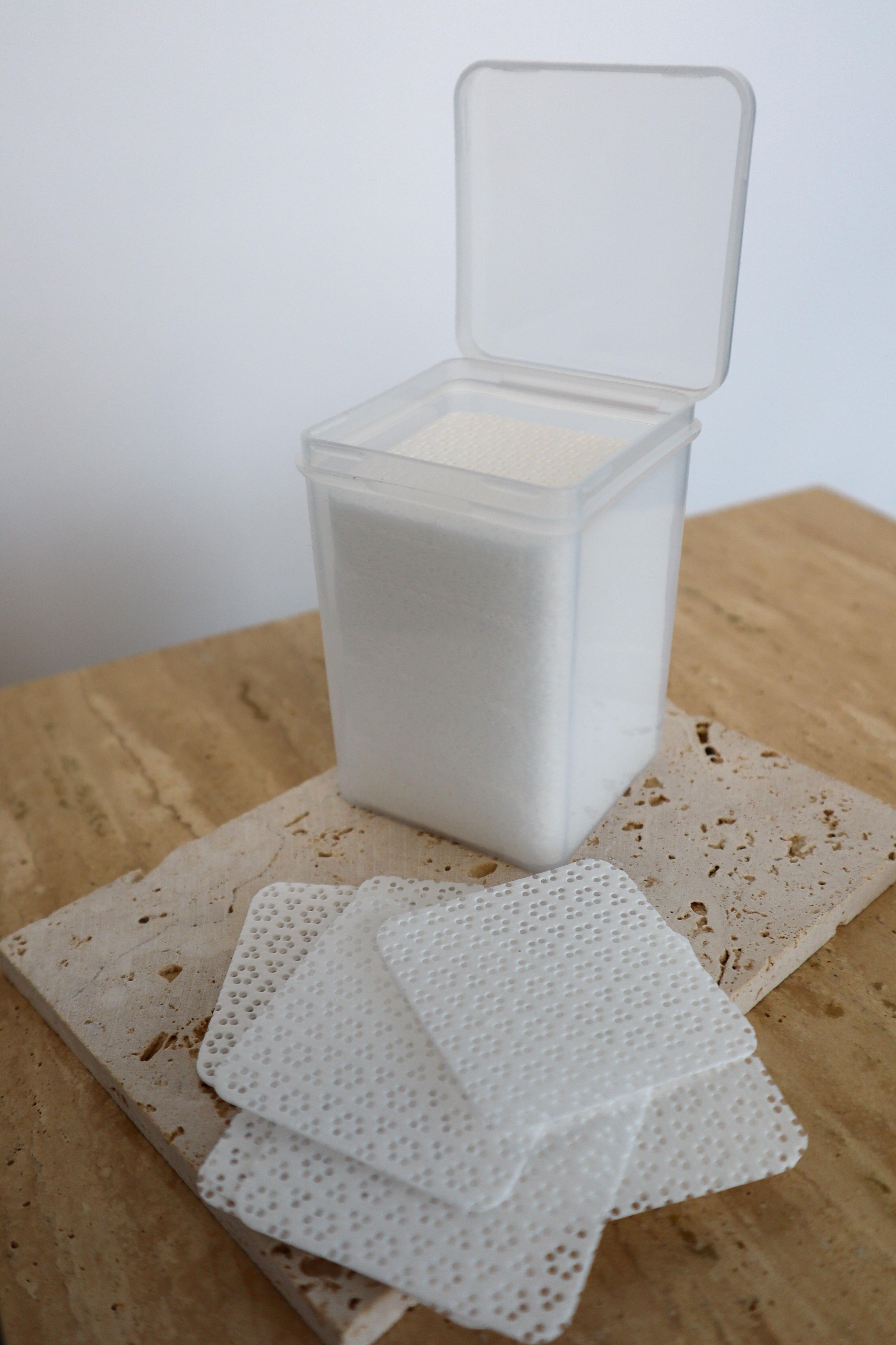 Clear container with white wipes on a wooden surface