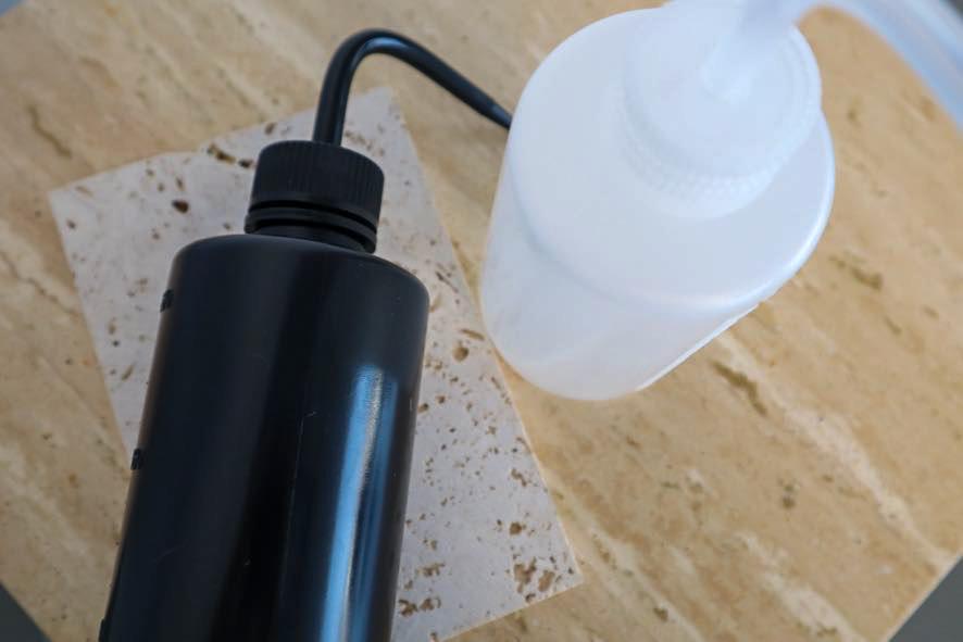 Black and white lash cleansing bottles on a wooden surface
